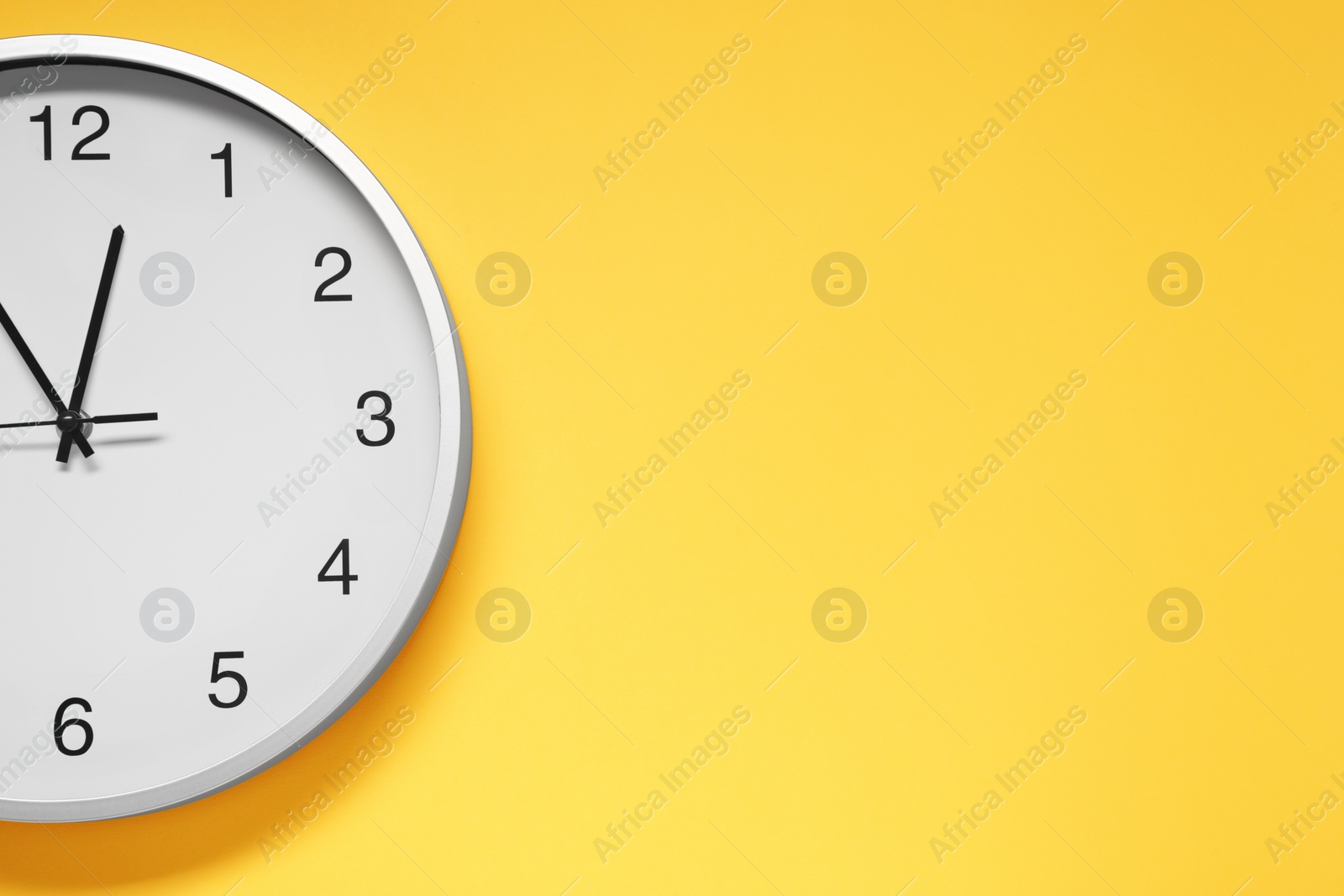 Photo of Stylish round clock on yellow background, top view with space for text. Interior element