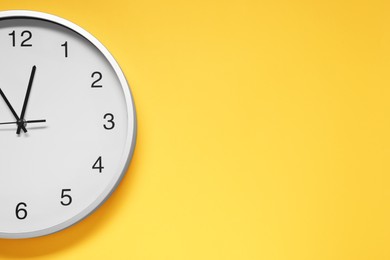 Stylish round clock on yellow background, top view with space for text. Interior element