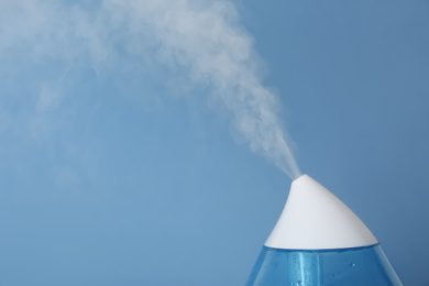 Modern air humidifier on light blue background, closeup. Space for text