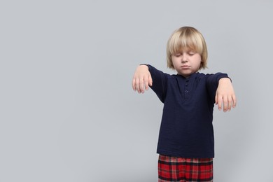 Photo of Boy in pajamas sleepwalking on light gray background, space for text