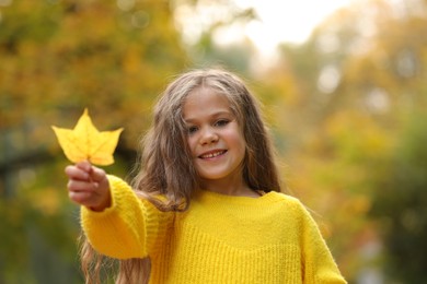 Photo of Portrait of happy girl with autumn dry leaf outdoors