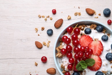 Delicious granola with fruits and nuts on wooden table, flat lay. Space for text