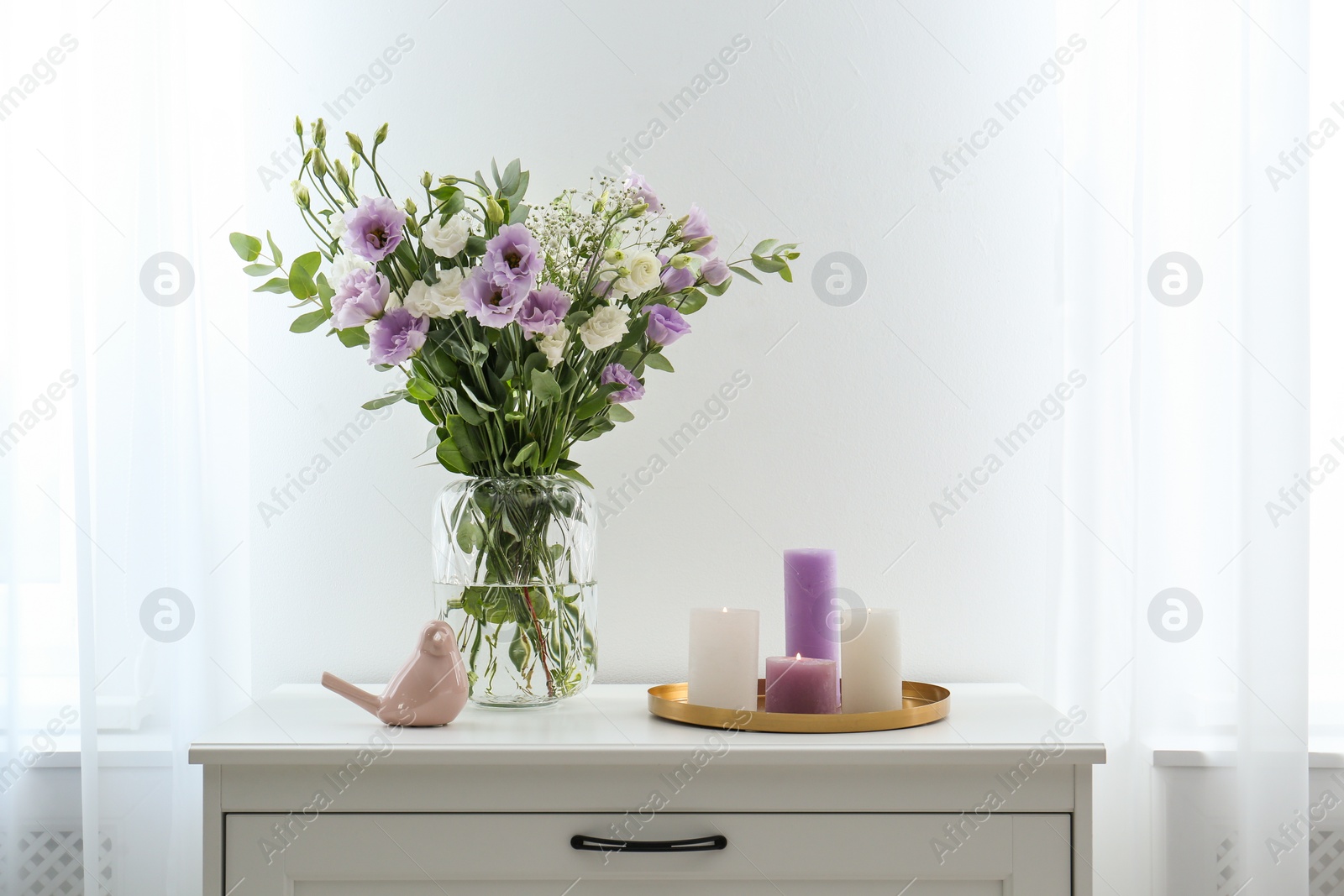 Photo of Bouquet of beautiful Eustoma flowers on chest of drawers in room. Space for text