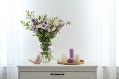 Photo of Bouquet of beautiful Eustoma flowers on chest of drawers in room. Space for text