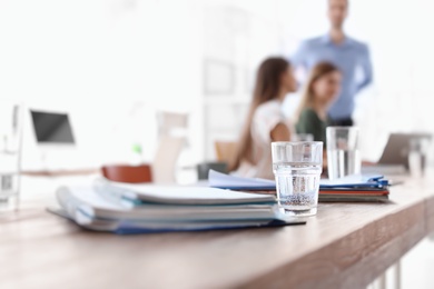 Photo of Folders, glass of water and people during business training  in office