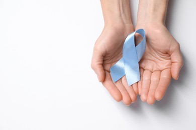 Photo of International Psoriasis Day. Woman with light blue ribbon as symbol of support on white background, top view. Space for text