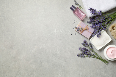 Cosmetic products and lavender flowers on light table, flat lay. Space for text