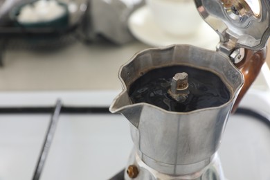 Photo of Brewing aromatic coffee in moka pot on stove indoors, closeup. Space for text