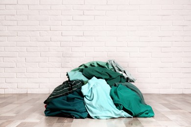 Pile of dirty clothes on floor near brick wall