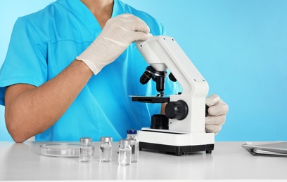 Photo of Male doctor using microscope at table, closeup. Medical object