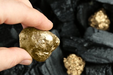 Woman holding gold nugget on blurred background, closeup. Space for text