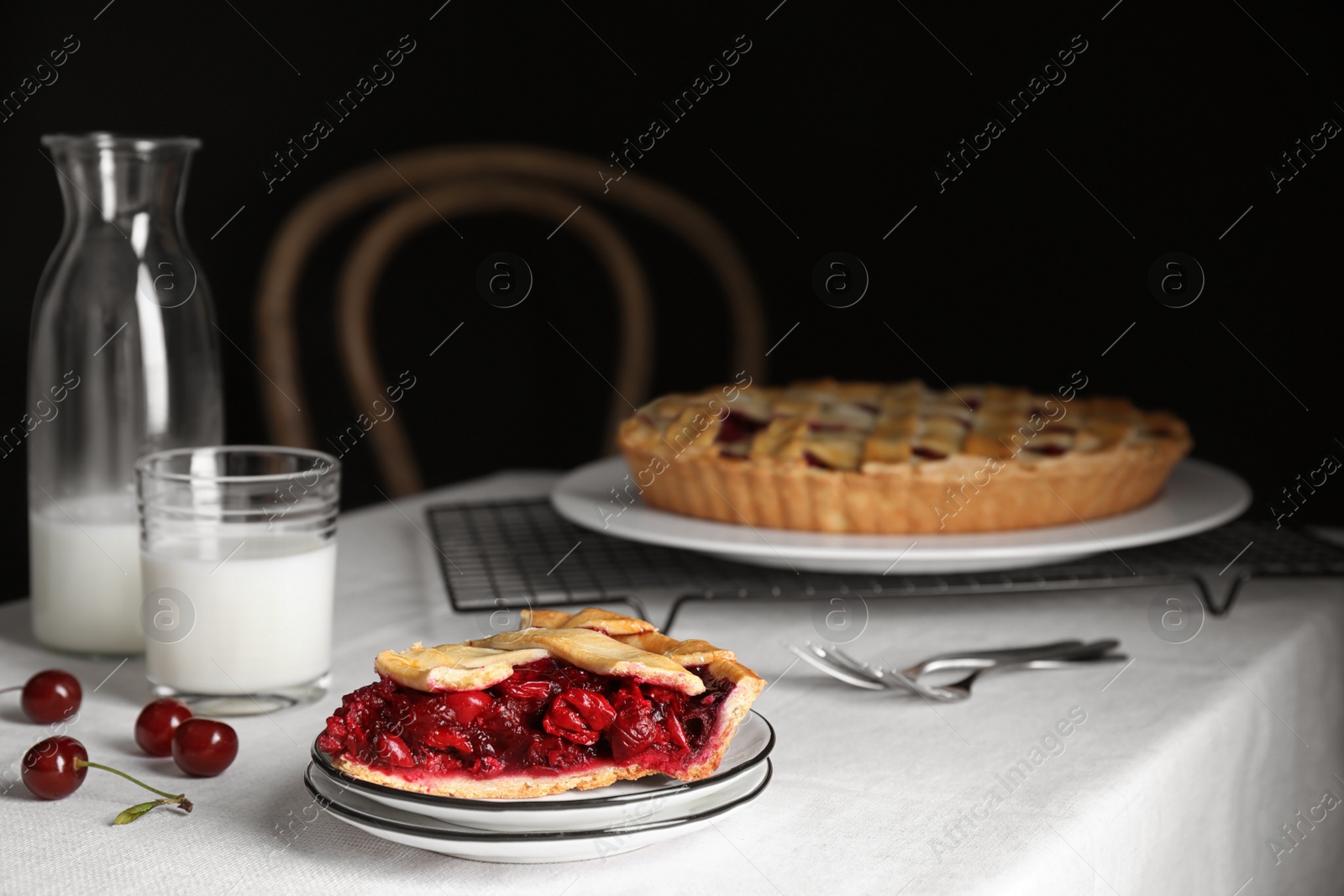 Photo of Slice of delicious fresh cherry pie on table against dark background