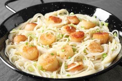 Delicious scallop pasta with green onion on grey table, closeup