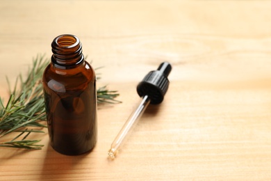 Bottle of natural tea tree oil, dropper and plant on table, space for text