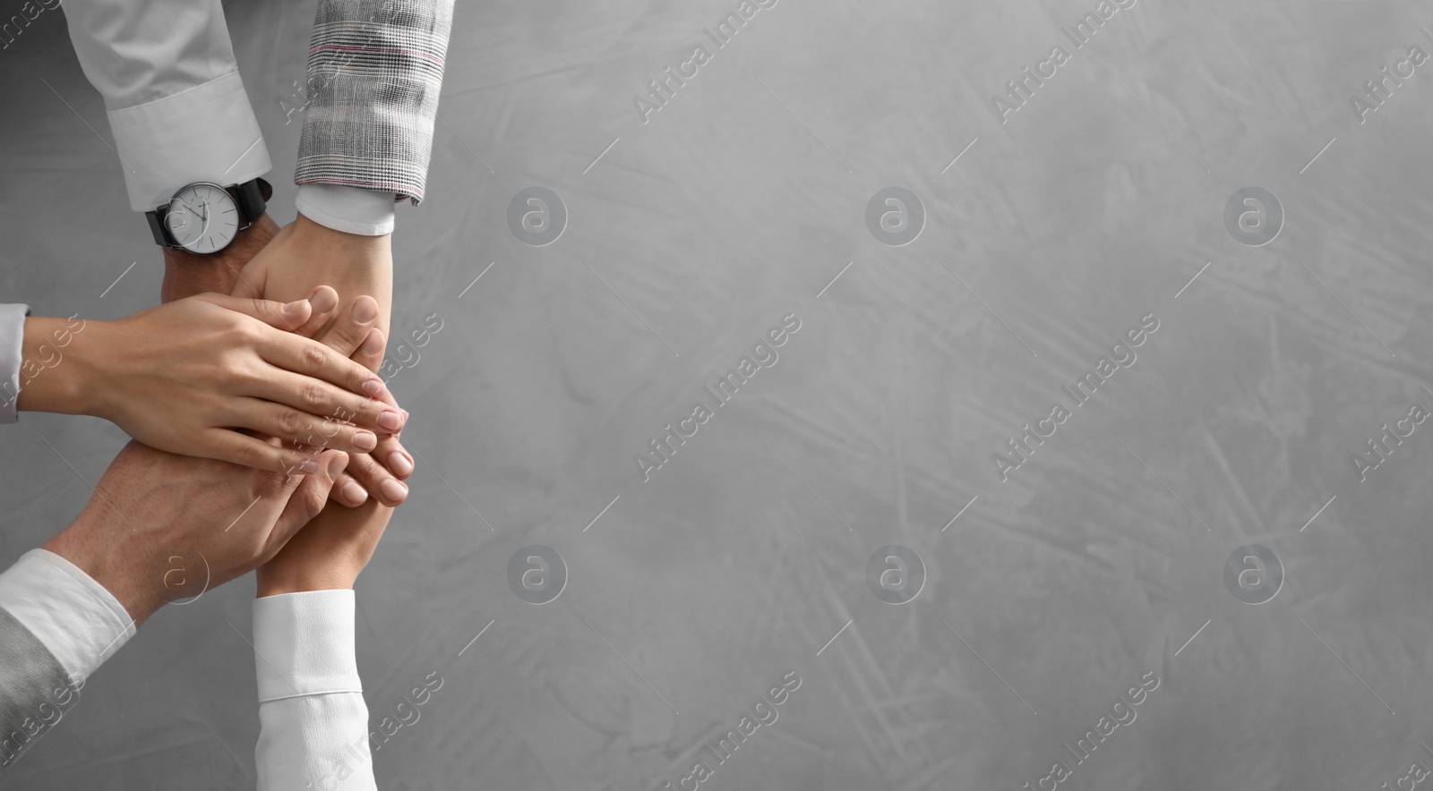 People holding hands together over grey stone background, top view with space for text. Unity concept Photo of People holding hands together over grey stone background, top view with space for text. Unity concept