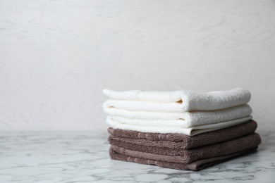 Photo of Stack of soft bath towels on table. Space for text