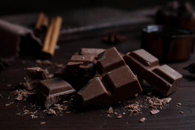 Photo of Pieces of delicious milk chocolate on wooden table