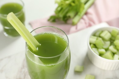 Glass of delicious celery juice and vegetables on white table, closeup