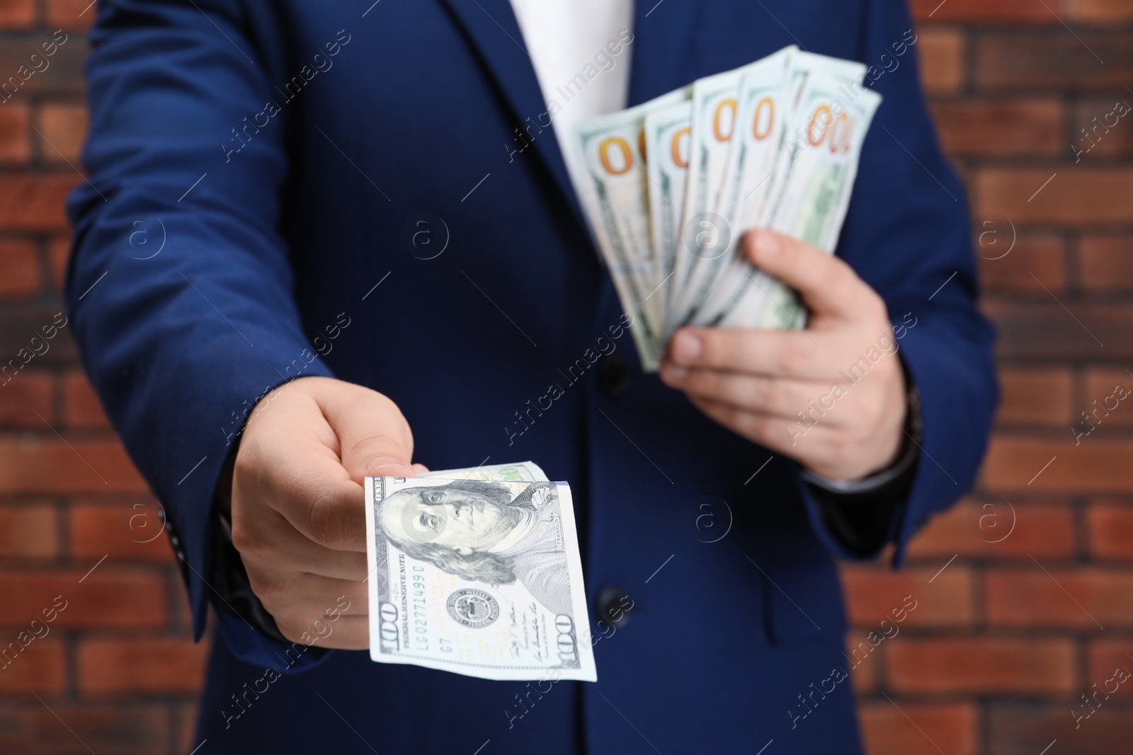 Photo of Man holding money near red brick wall, closeup. Currency exchange