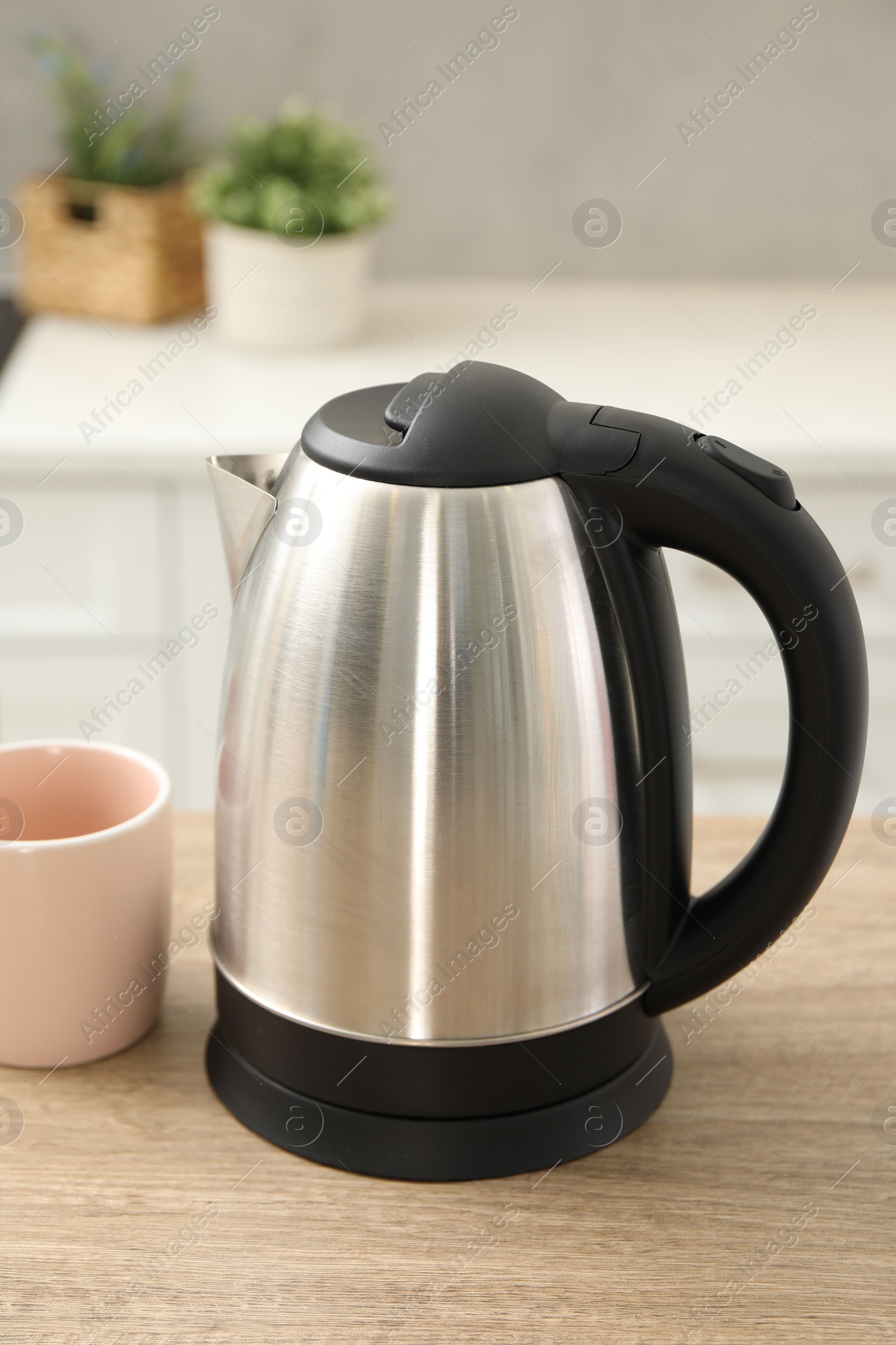 Photo of Modern electric kettle and cup on table in kitchen