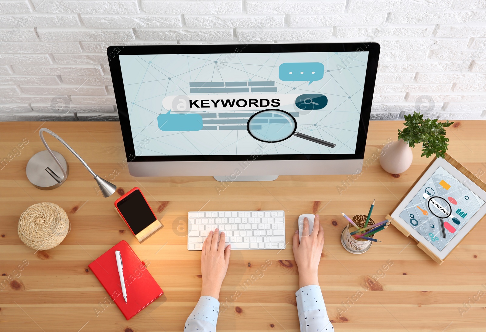 Image of Woman searching keywords with computer at wooden table, top view