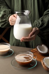 Photo of Woman with jugtasty coconut milk at table, closeup