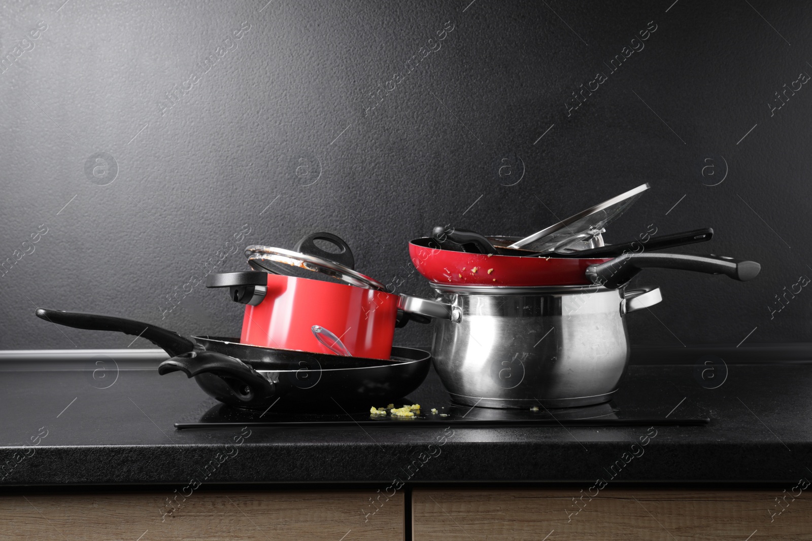 Photo of Stacks of dirty kitchenware on cooktop in kitchen