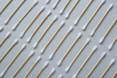 Many wooden cotton buds on light grey background, flat lay