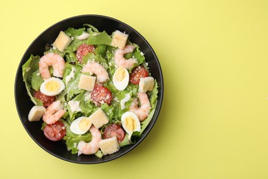 Delicious Caesar salad with shrimps on yellow background, top view. Space for text