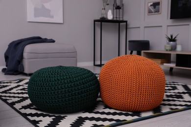 Different stylish poufs on floor in living room