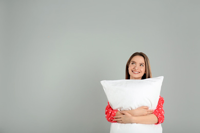 Photo of Young woman with pillow on grey background. Space for text