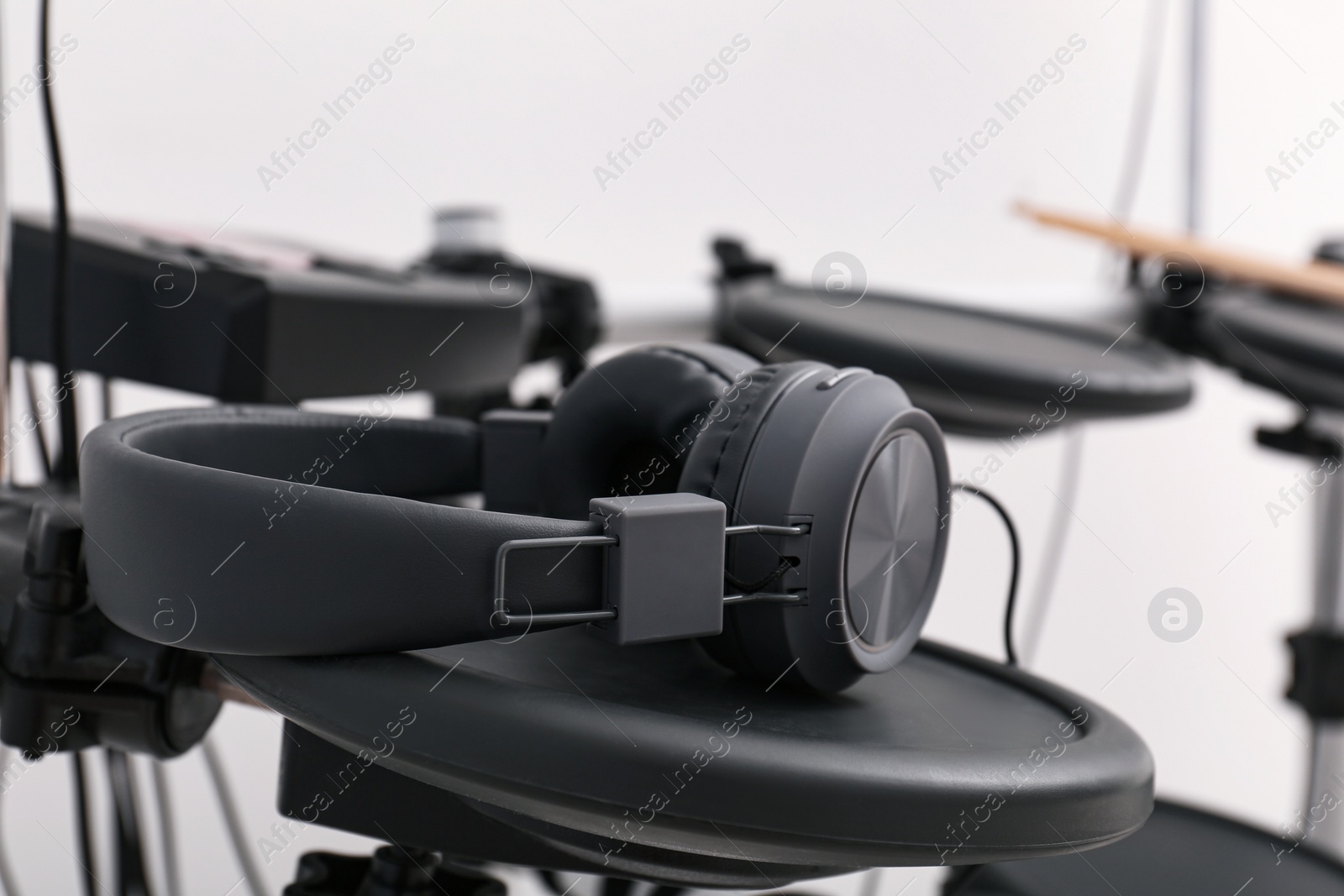 Photo of Modern electronic drum kit with headphones indoors, closeup. Musical instrument