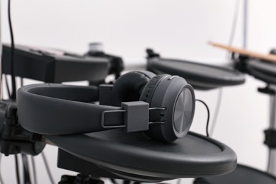 Photo of Modern electronic drum kit with headphones indoors, closeup. Musical instrument