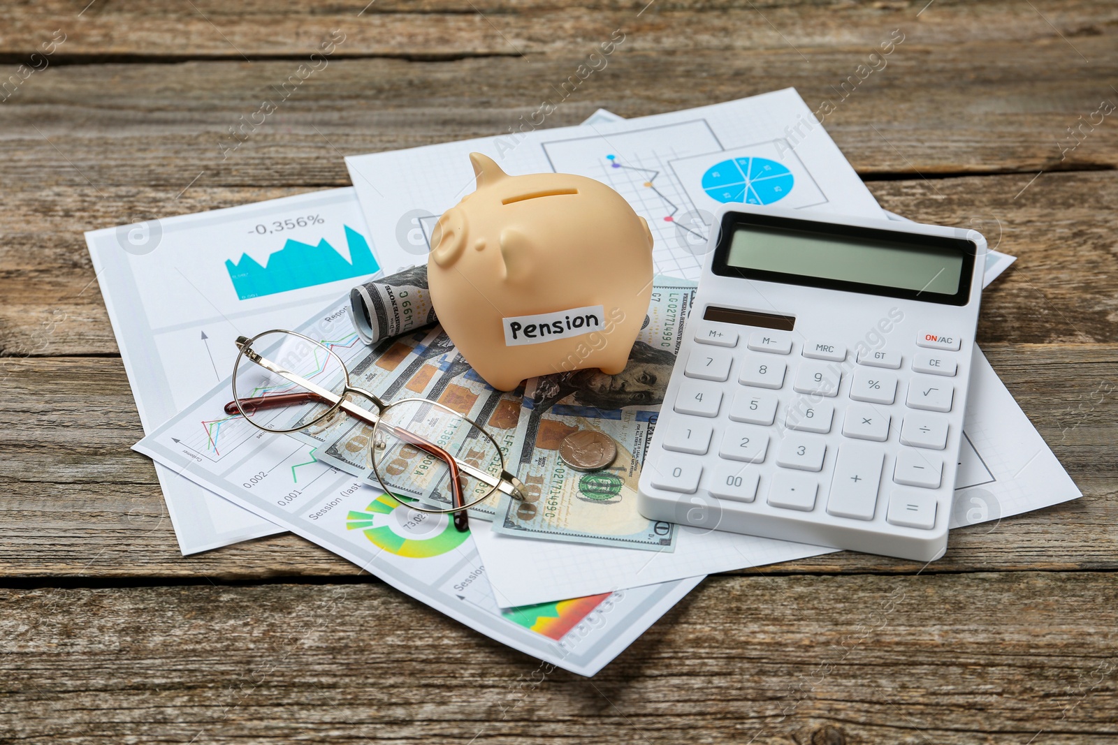 Photo of Piggy bank with word Pension, banknotes, glasses, calculator and diagrams on wooden table. Retirement savings