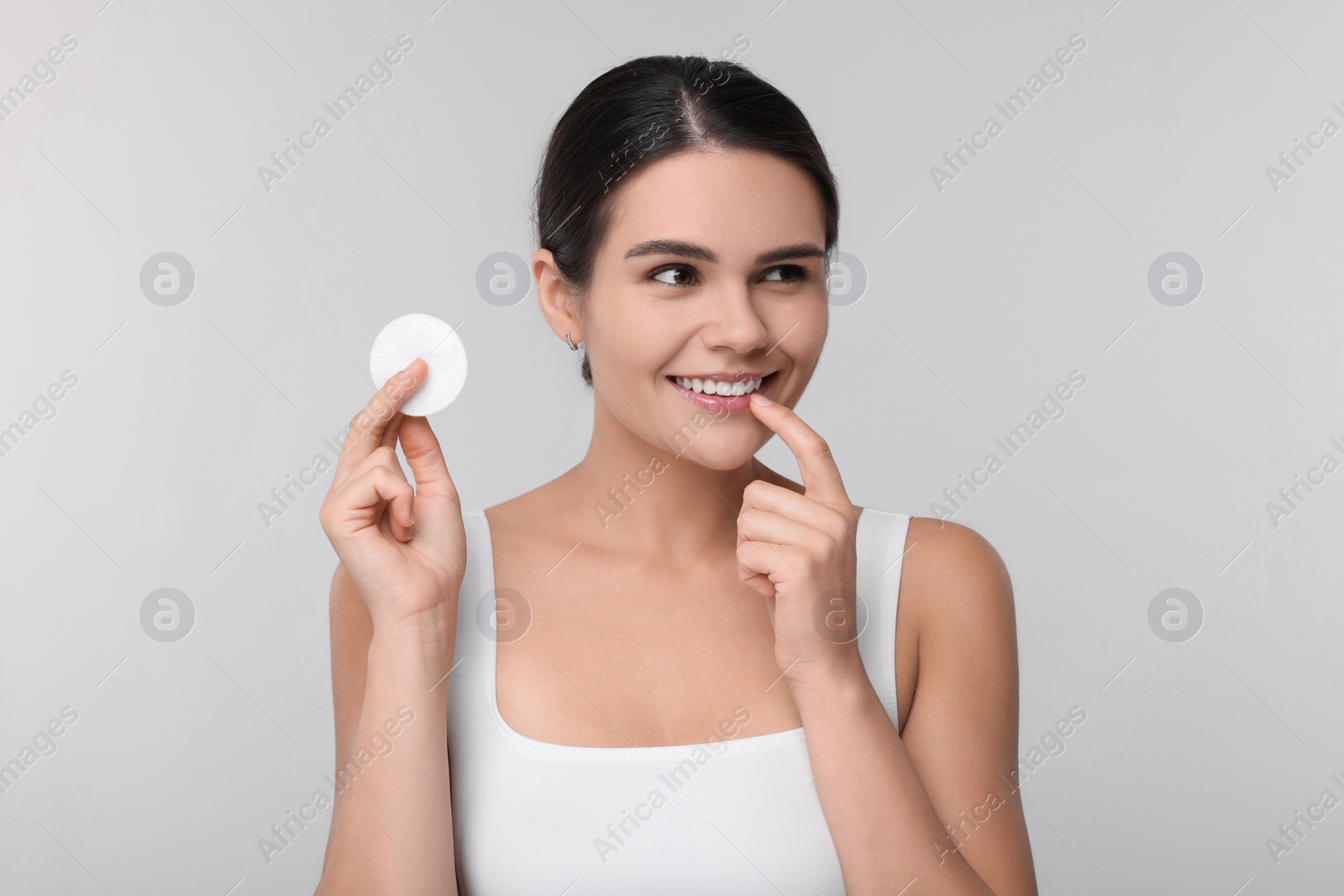 Photo of Young woman with cotton pad on light grey background