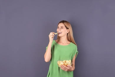 Woman eating potato chips on grey background