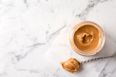 Photo of Jar with creamy peanut butter on light background