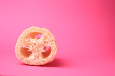 Photo of Natural loofah sponge on pink background, space for text