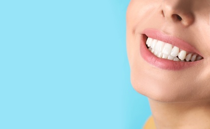 Young woman with healthy teeth on color background, closeup. Space for text