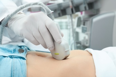 Doctor conducting ultrasound examination of internal organs in clinic, closeup