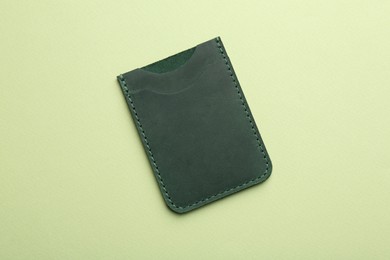 Empty leather card holder on light green background, top view