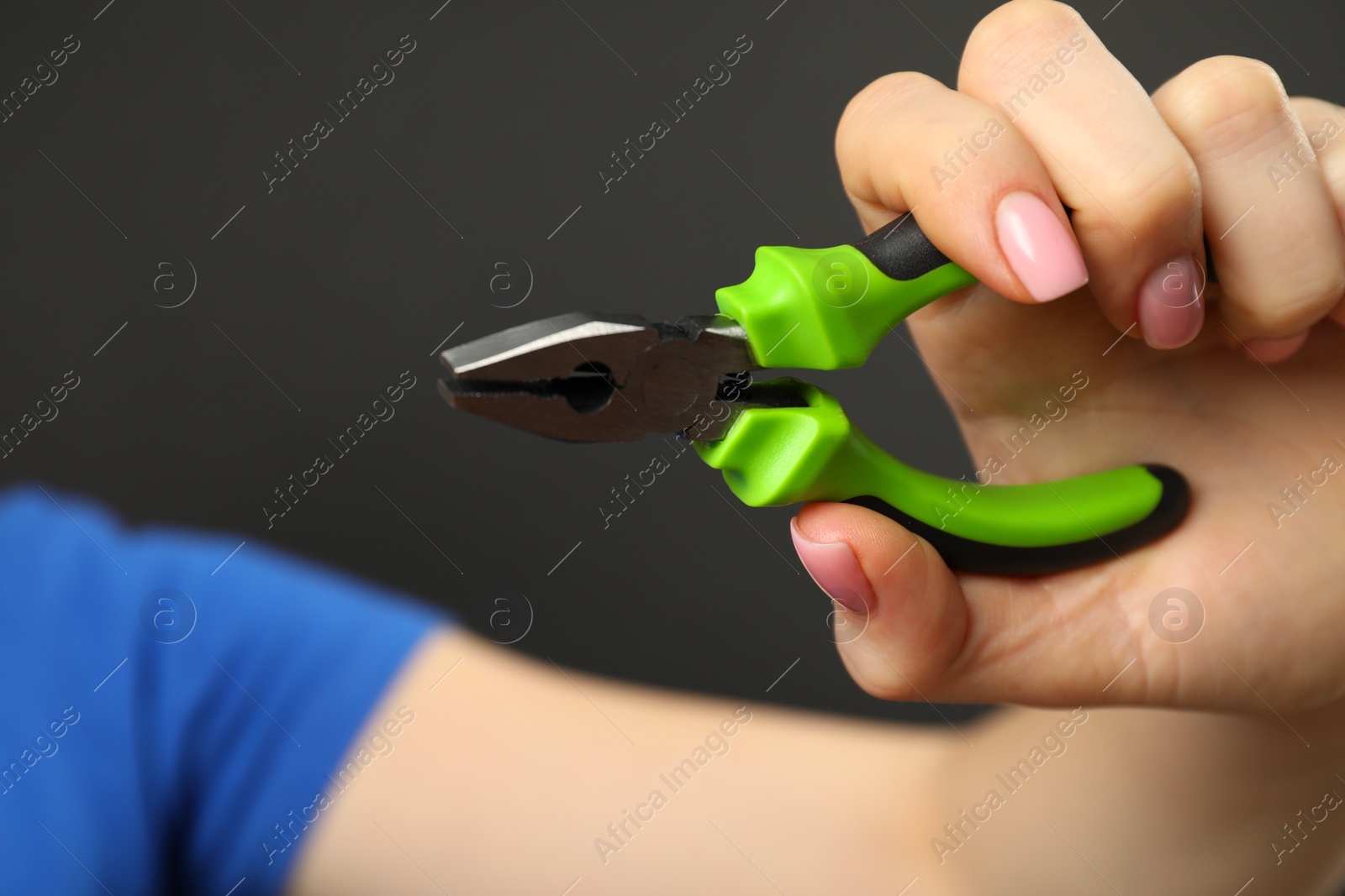 Photo of Woman with combination pliers on dark background, closeup. Space for text