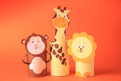 Photo of Toy monkey, giraffe, and lion made from toilet paper hubs on orange background. Children's handmade ideas