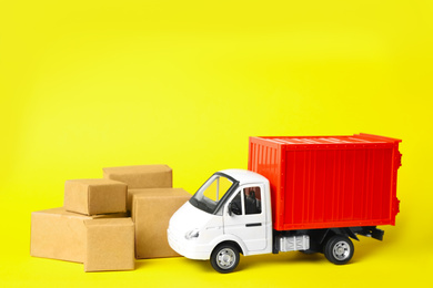 Photo of Toy truck with boxes on yellow background. Logistics and wholesale concept