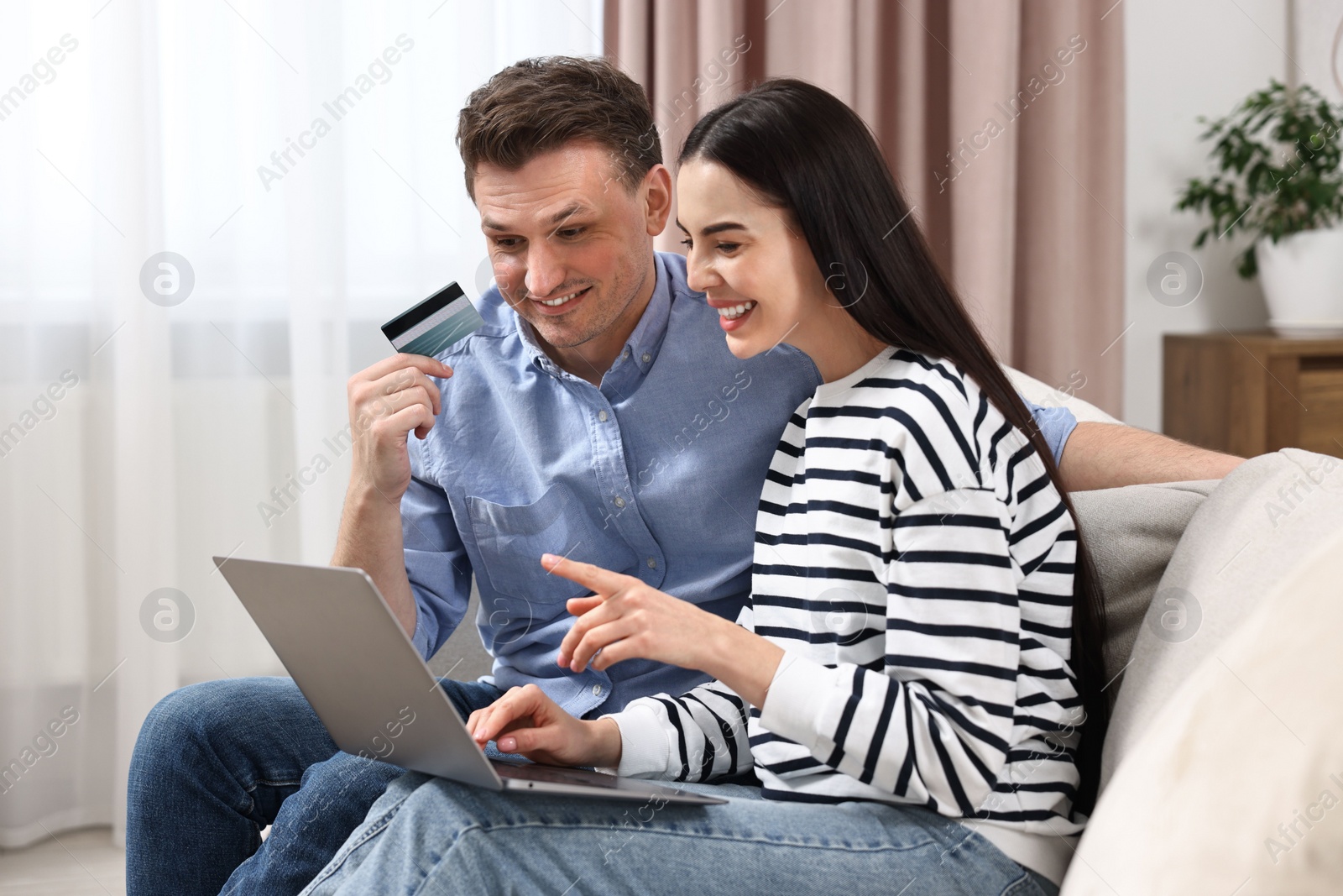 Photo of Happy couple with laptop and credit card shopping online together at home