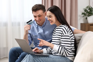 Happy couple with laptop and credit card shopping online together at home