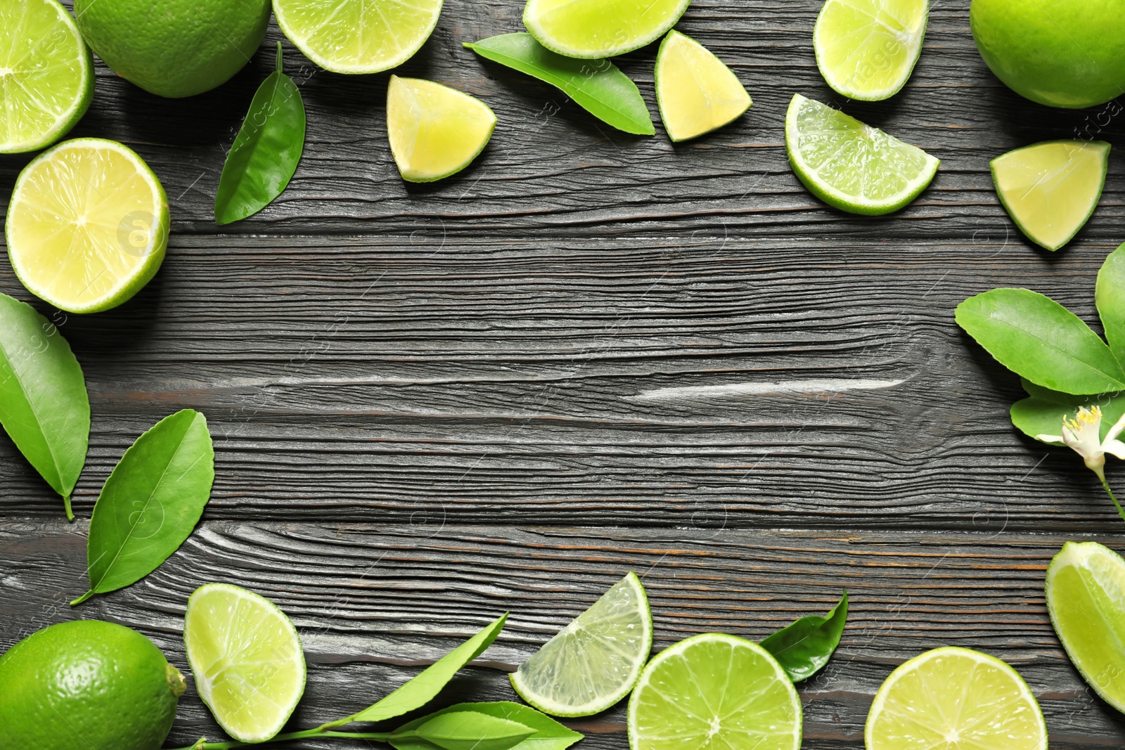 Photo of Frame of fresh ripe limes on wooden background, top view