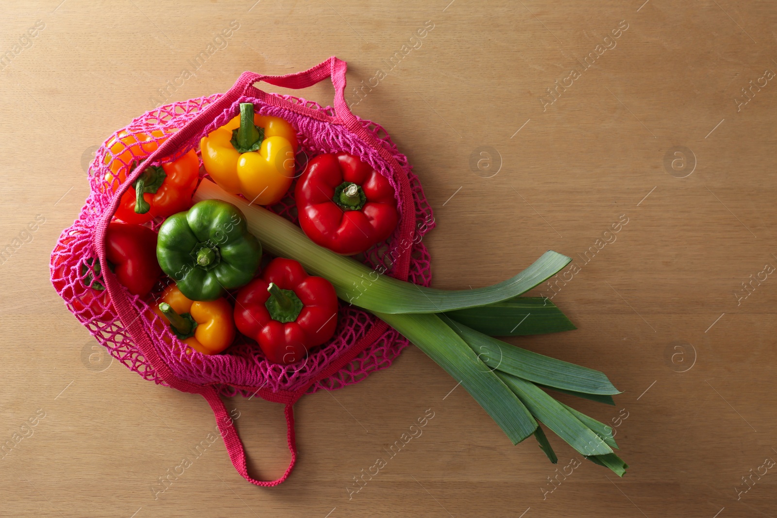 Photo of Different fresh vegetables in eco mesh bag on wooden table, top view