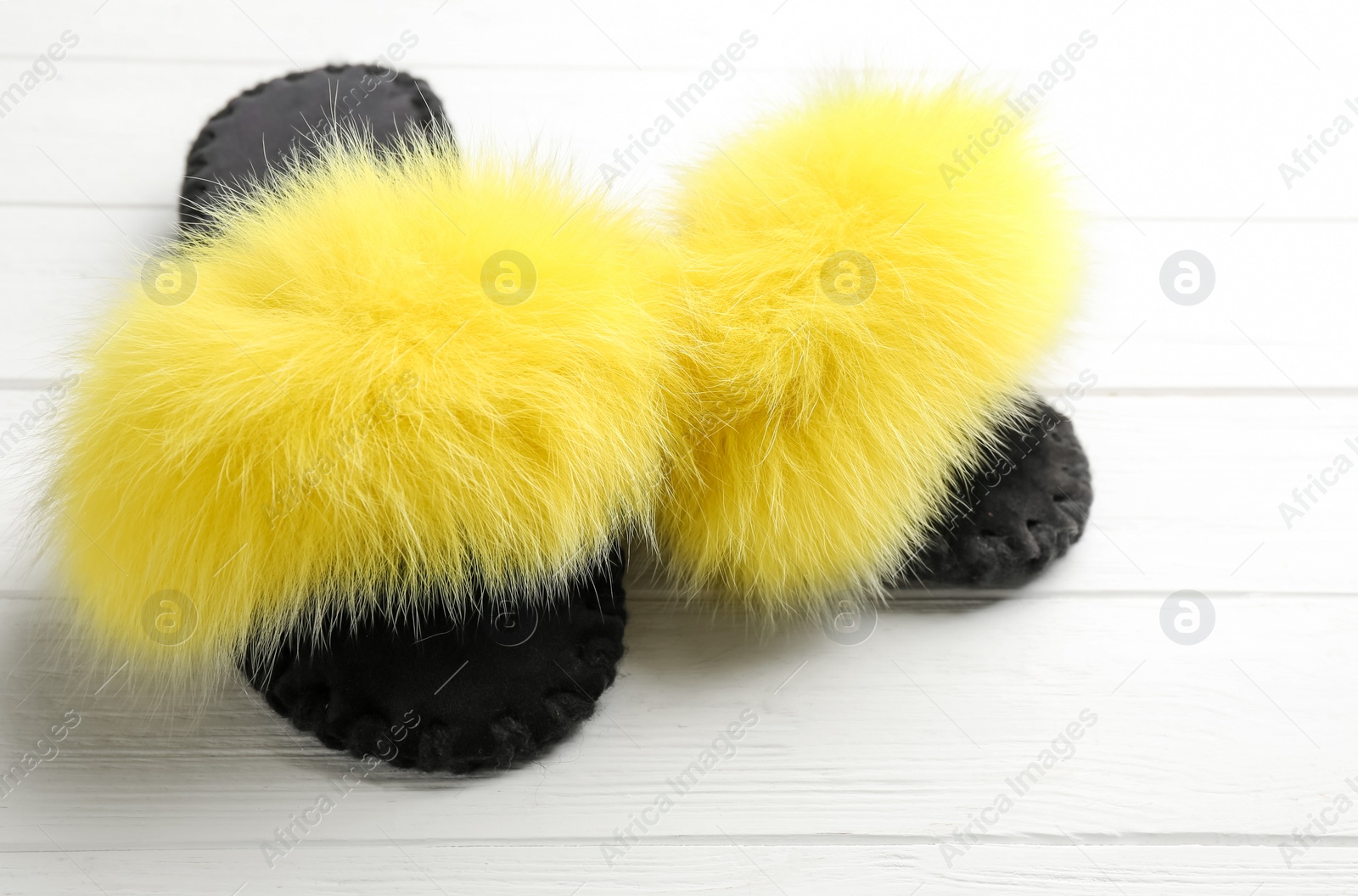 Photo of Pair of soft slippers on white wooden background, closeup