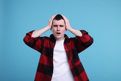 Portrait of surprised man on light blue background